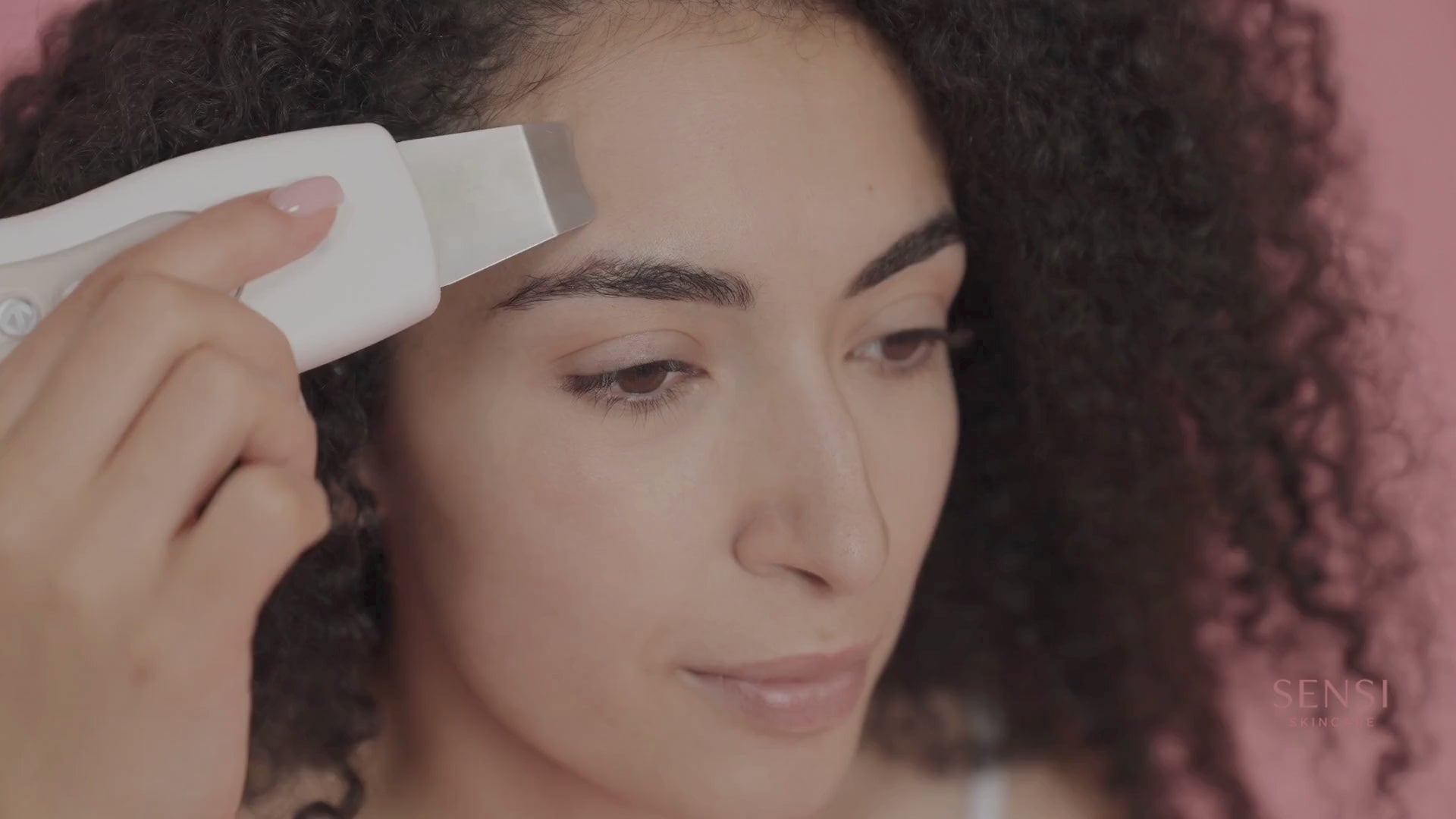 Load video: A beautiful woman using the SENSI Skin 3-in-1 Ultrasonic Facial Spatula to gently cleanse and exfoliate her face, showcasing a glowing, spa-like skincare routine at home.